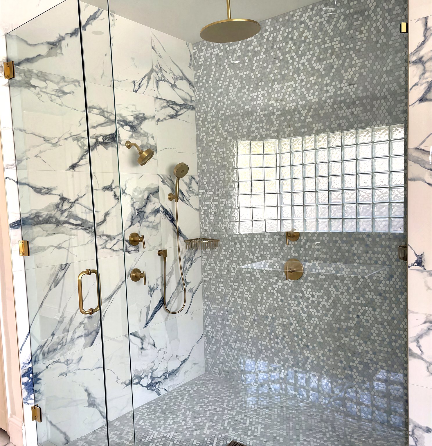 Glass-enclosed marble shower with gold rain head