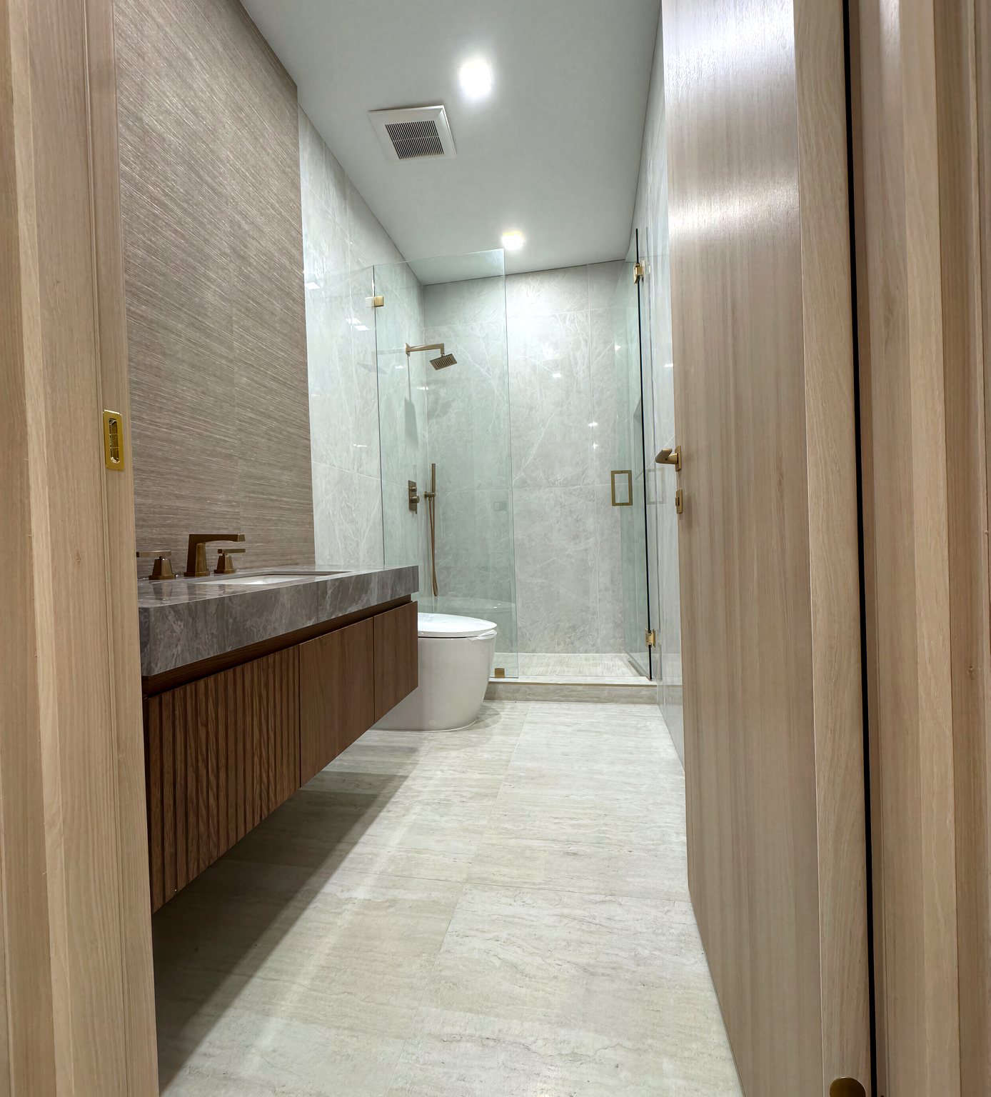 Marble bathroom with floating wood vanity and gold fixtures